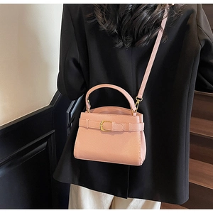 Détail du sac à bandoulière rose en cuir litchi avec boucle en métal et finitions dorées