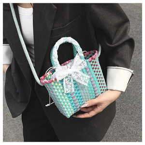 Detail of colorful woven basket bag with white lace bow and matching lace-wrapped handles