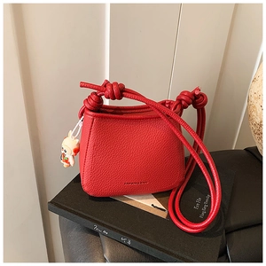 Detailed view of red pebble leather bucket bag with knot strap and cute bunny charm