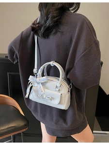 Light blue-grey mini pillow handbag with bow and silk scarf worn as crossbody bag