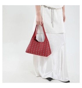 Detailaufnahme der roten Handtasche aus Leder mit silbernen Ösen und Nieten-Dekor