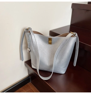 Detail of silver bucket bag showing lychee leather texture and golden twist lock