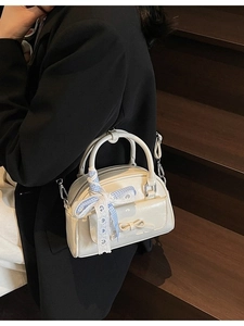 Mini white Boston bag for women with bow detail and ribbon, shown on a stylish model