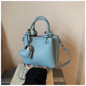 Detail of light blue lychee pattern bucket bag with a matching leather heart pendant