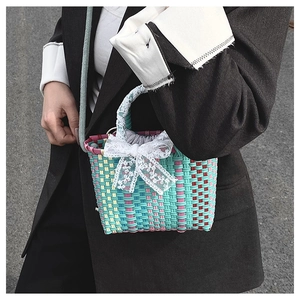 Detail of hand-woven colorful basket bag with delicate lace bow and drawstring inner liner