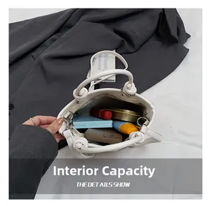 Macro view of interior storage capacity in white pebble leather bucket bag with items