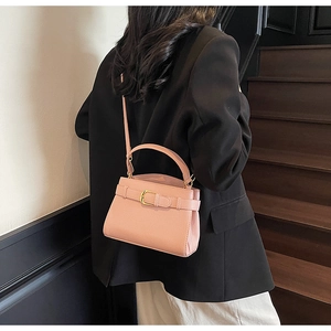 Détail de sac à main rose avec texture litchi et boucle dorée porté à l'épaule