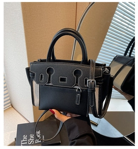 Detail of black lychee leather bag with white stitching and canvas side panel texture