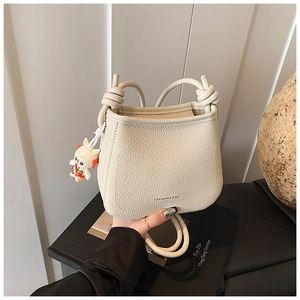 Detail of off-white lychee pattern bucket bag with knot handle and cartoon charm