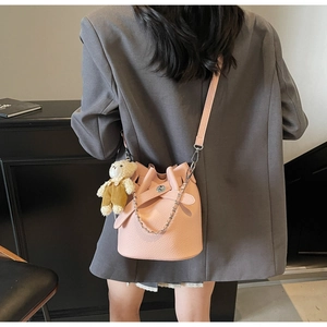 Pink lychee-textured bucket bag with silver chain and cute bear charm on a model