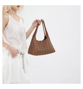 Close-up of deep brown leather tote bag with silver metal eyelet decorative details