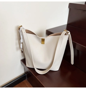 Detail of lychee pattern leather bucket bag showing golden metal buckle and woven knot