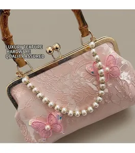 Detail of pink floral embroidery bag with bamboo handle and pearl rhinestone chain