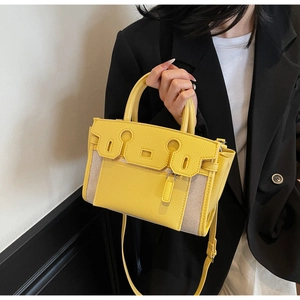 Detail of yellow lychee leather handbag with canvas stitching and long shoulder strap