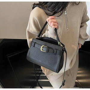 Détail du sac à main noir en cuir grainé avec bandoulière réglable et boucle en métal