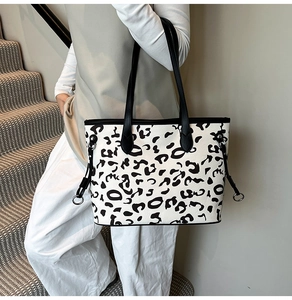 Modella che indossa una borsa tote leopardata con manici neri su una scala moderna