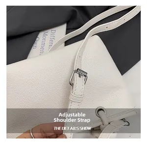 Detail view of the adjustable shoulder strap and silver metal buckle on white leather bag