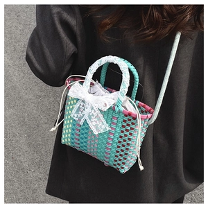 Detailed woven texture of a colorful crossbody bag with white lace bow and drawstring
