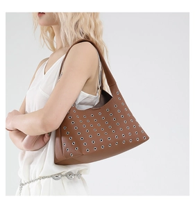 Detail of brown hobo bag featuring silver metal eyelets and lychee grain leather texture