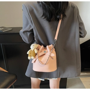 Pink bucket bag detail with teddy bear charm and chain strap on grey blazer