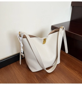 Detail of cream white pebbled leather bag with gold twist lock and woven charm detail