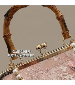 Detail of bamboo handle and engraved metal clasp on pink embossed fabric pearl bag