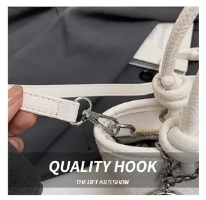 Detailed view of silver metal hooks and zipper on a white pebble textured bucket bag