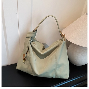 Close-up of green pleated tote bag featuring knotted shoulder strap and gold hardware detail