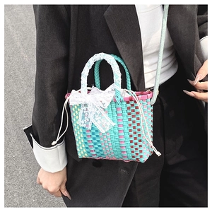 Detail of multi-color woven handbag with lace bow and drawstring inner bag