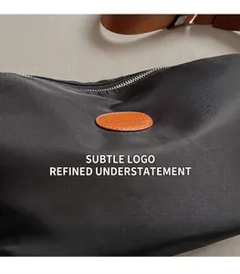 Close-up of black oxford nylon fabric and orange leather logo on the stylish sling bag