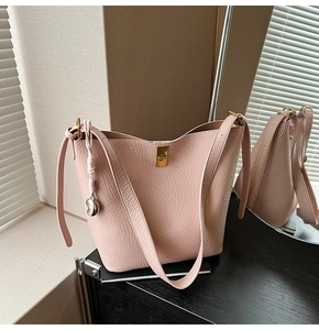 Detailed close-up of pink lychee grain leather bucket bag with golden buckle and heart charm