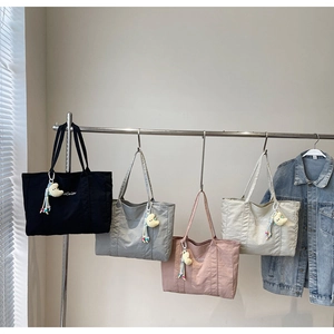 Detail of four colorful nylon tote bags with letter embroidery and moon plush pendants