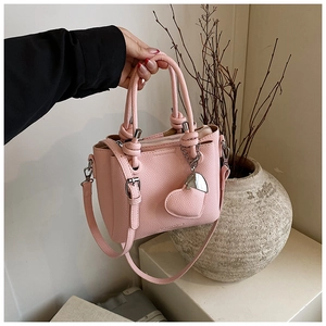 Detail of light pink bucket bag with heart pendant and pebbled leather texture