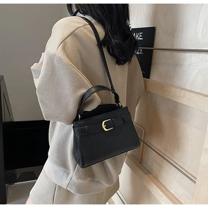 Détail du sac à main en cuir noir grainé avec boucle dorée et bandoulière fine