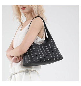 Detail of black shoulder bag featuring rows of silver metal eyelets and leather strap