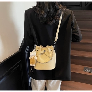 Detail of light yellow bucket bag with lychee texture and cute bear plush charm
