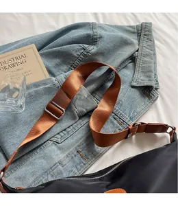 Close-up of black Oxford cloth crossbody bag with adjustable wide brown nylon strap