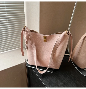 Detailed macro view of pink litchi leather bucket bag with gold twist lock closure