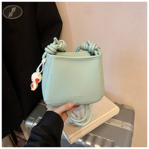Detail of light green litchi texture crossbody bag with cute bunny pendant charm
