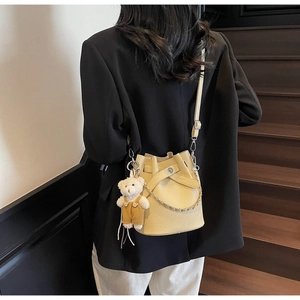 Close-up of a yellow lychee pattern bucket bag with chain strap and cute bear charm