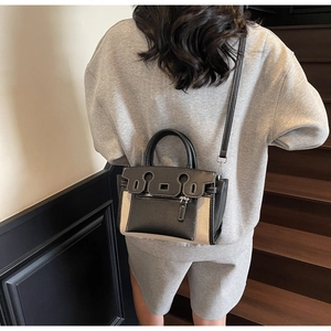 Detail of color-block bucket bag showing leather stitching and textured canvas materials