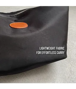 Detail of black nylon dumpling bag featuring a brown leather label and silver zipper