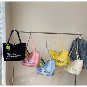 Detailed view of five colorful canvas tote bags with floral charms on display hangers
