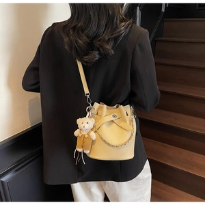 Detail of pale yellow bucket bag with lychee texture and bear charm on model back
