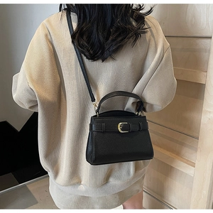 Vue arrière du modèle portant un sac à main noir en cuir litchi avec fermoir doré