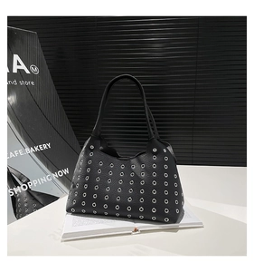Detail of black pebbled leather handbag with decorative silver metal grommets