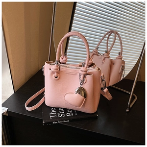 Detail of pink lychee texture leather bucket bag with knot handle and heart charm