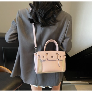 Detail of pink and beige Kelly bag showing silver hardware and adjustable strap on model