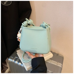 Detail of mint green bucket bag with lychee texture and cute white rabbit pendant