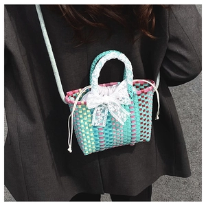 Detail of colorful woven mini bag with white lace handles and a cute ribbon bow